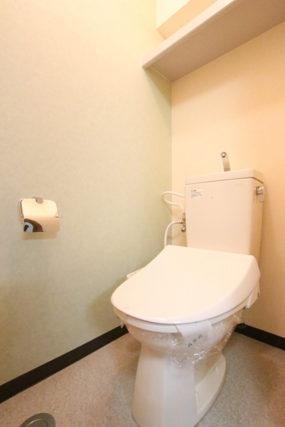 ライトグリーンの壁紙を使用したトイレ、シャワートイレ付き。