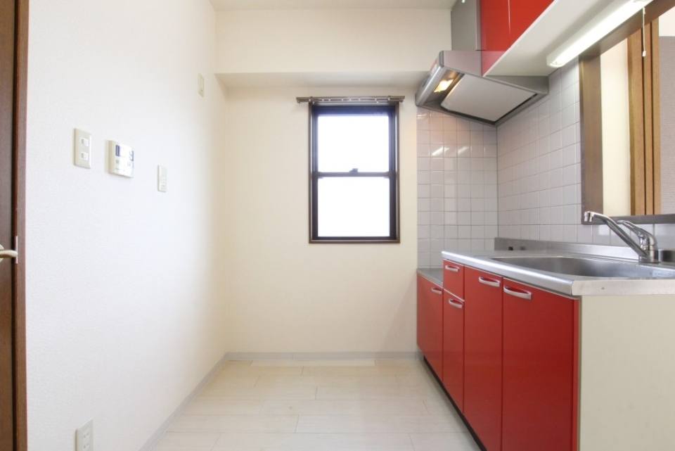 インパクト大のレッドキッチン、角部屋の特権＋αの窓がキッチン空間を明るくする。
