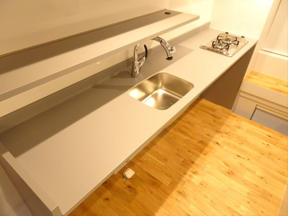 キッチンは居室に合わせた無機質かつシンプルなデザイン。横に広く作業スペースたっぷりです。