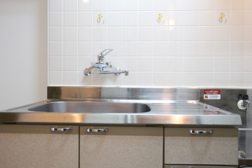 白いタイルに囲まれたキッチンは、シングルレバー水栓へ交換済。
