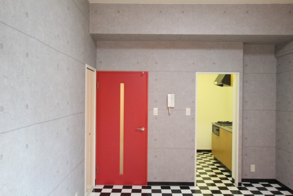 チェックフロアとコンクリート風壁と赤い扉がこのお部屋特徴。