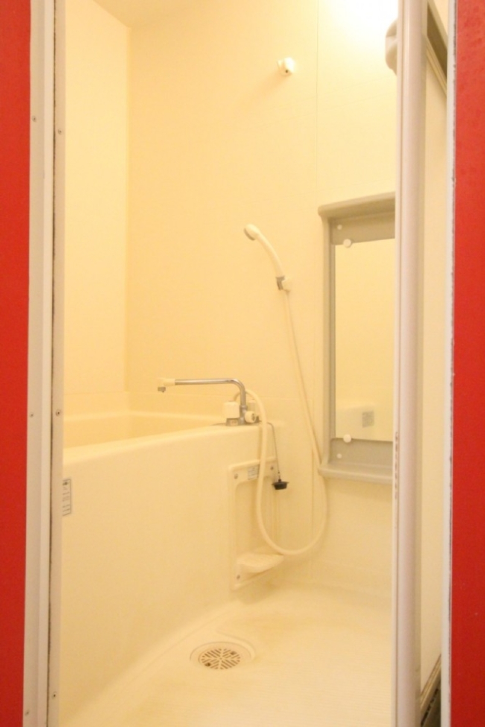 シンプルな浴室空間、ドア枠も赤く縁どられている。