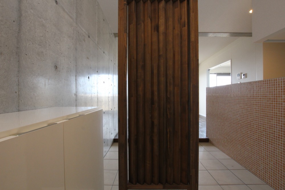玄関の扉を開けると、アジアンテイストな木製ルバーフェンス。