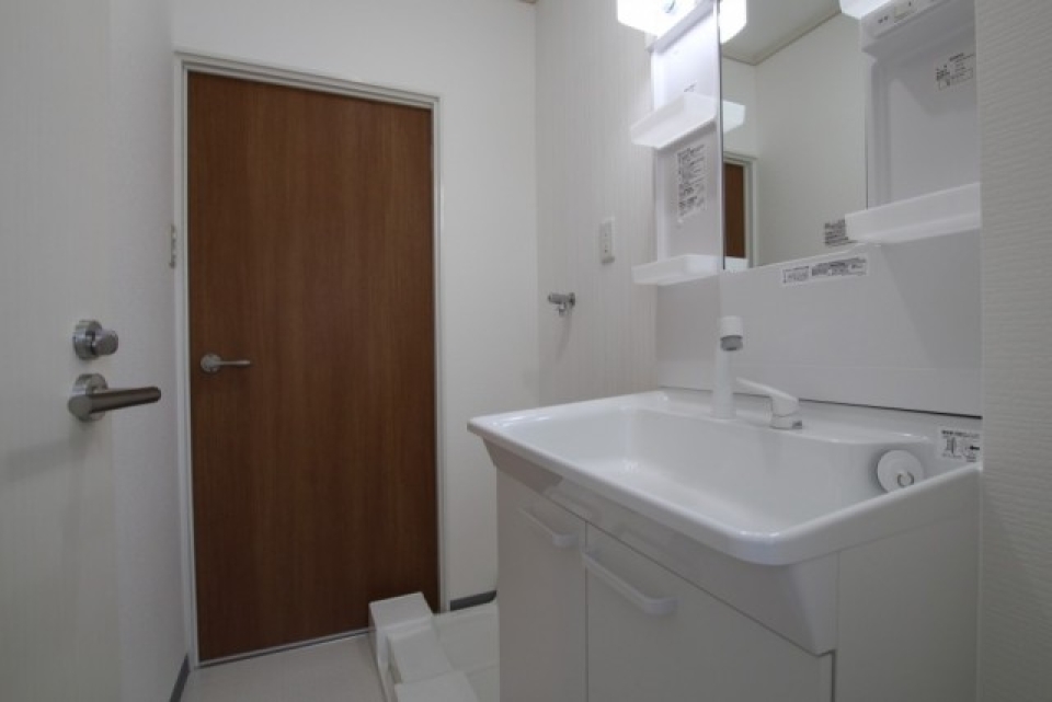 白１色の脱衣所にトイレの扉がアクセント。