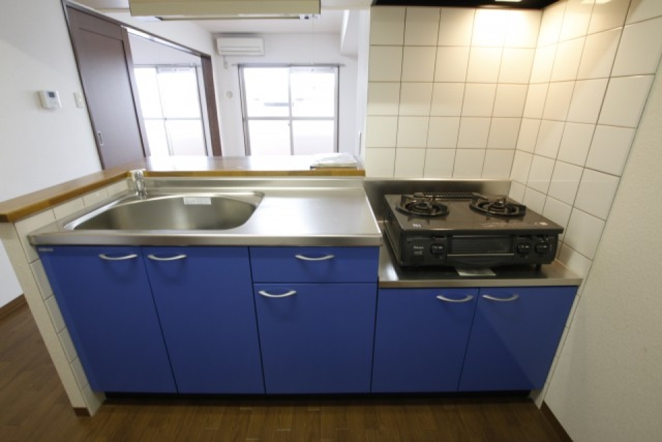 青色のキッチンがポイント。対面タイプです。