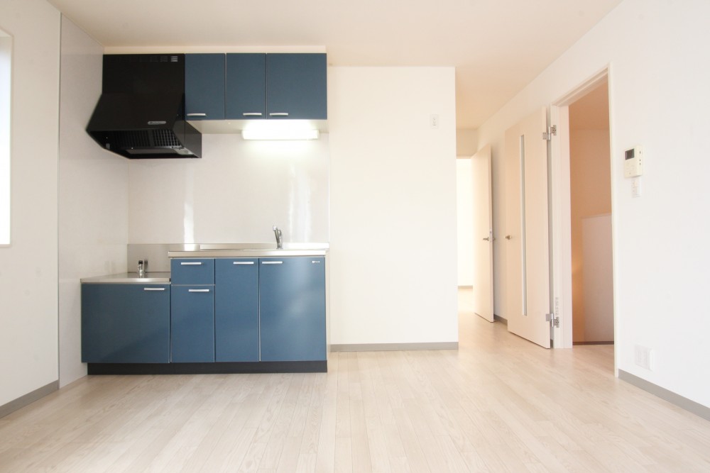 白い空間に、アパート外装と同じ青いキッチンのアクセントがクール