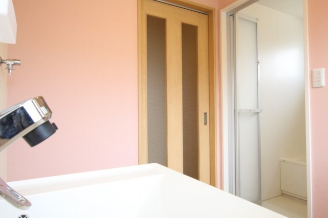 洗面・脱衣スペースの壁紙はかわいらしい桜色。