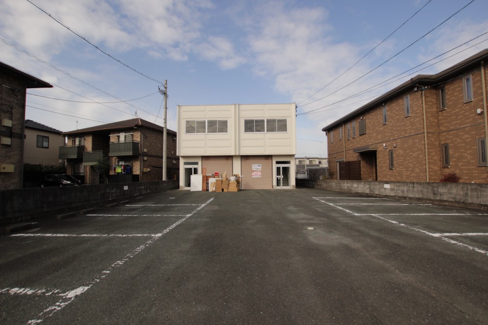 広い駐車場の奥に建物があります。