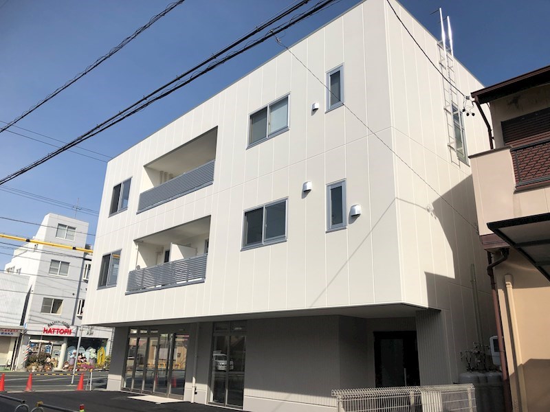 真っ白な壁が印象的。ベランダの部分だけ大きく空いているのがまた印象的です。1階はテナントになっています。