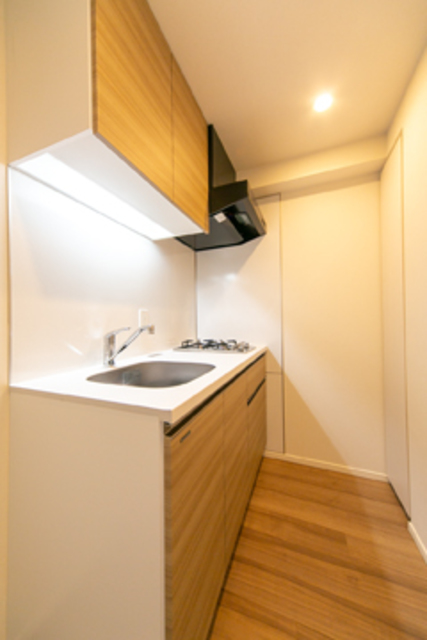 フロアに合わせて木目調のパネルが採用された、２口コンロのキッチン。※写真は同タイプ住戸です。