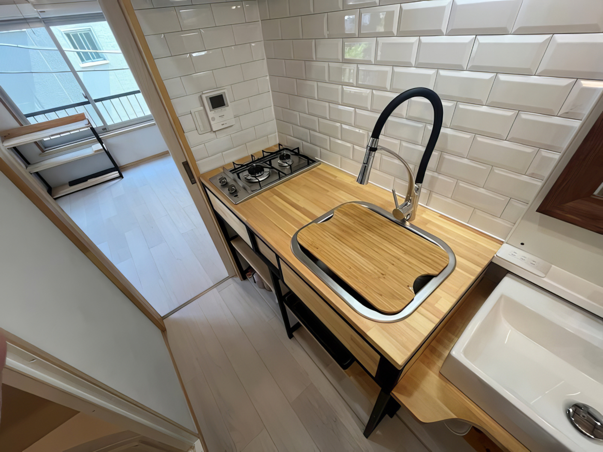 スタイリッシュな2口コンロと、アイアンに色合わせしたグースネック水栓にこだわりを感じる。お隣には洗面台と鏡