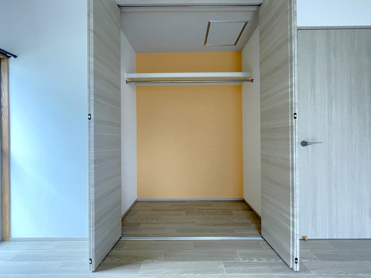 クローゼットを開くと奥のクロスが明るいオレンジ色で気分も明るくなりそう