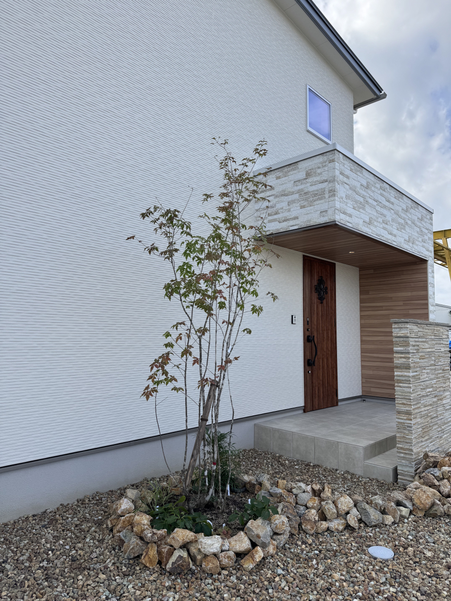 植物とブラウンロック、そして白い外壁のコントラストが素敵